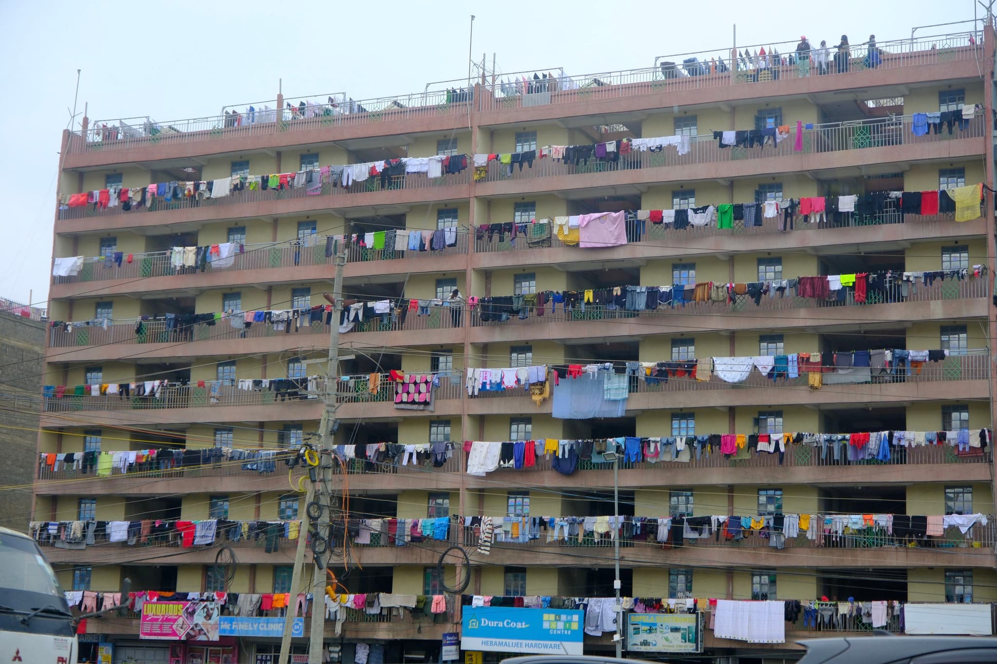 A multi-story residential building with numerous balconies, each displaying colorful laundry hanging out to dry