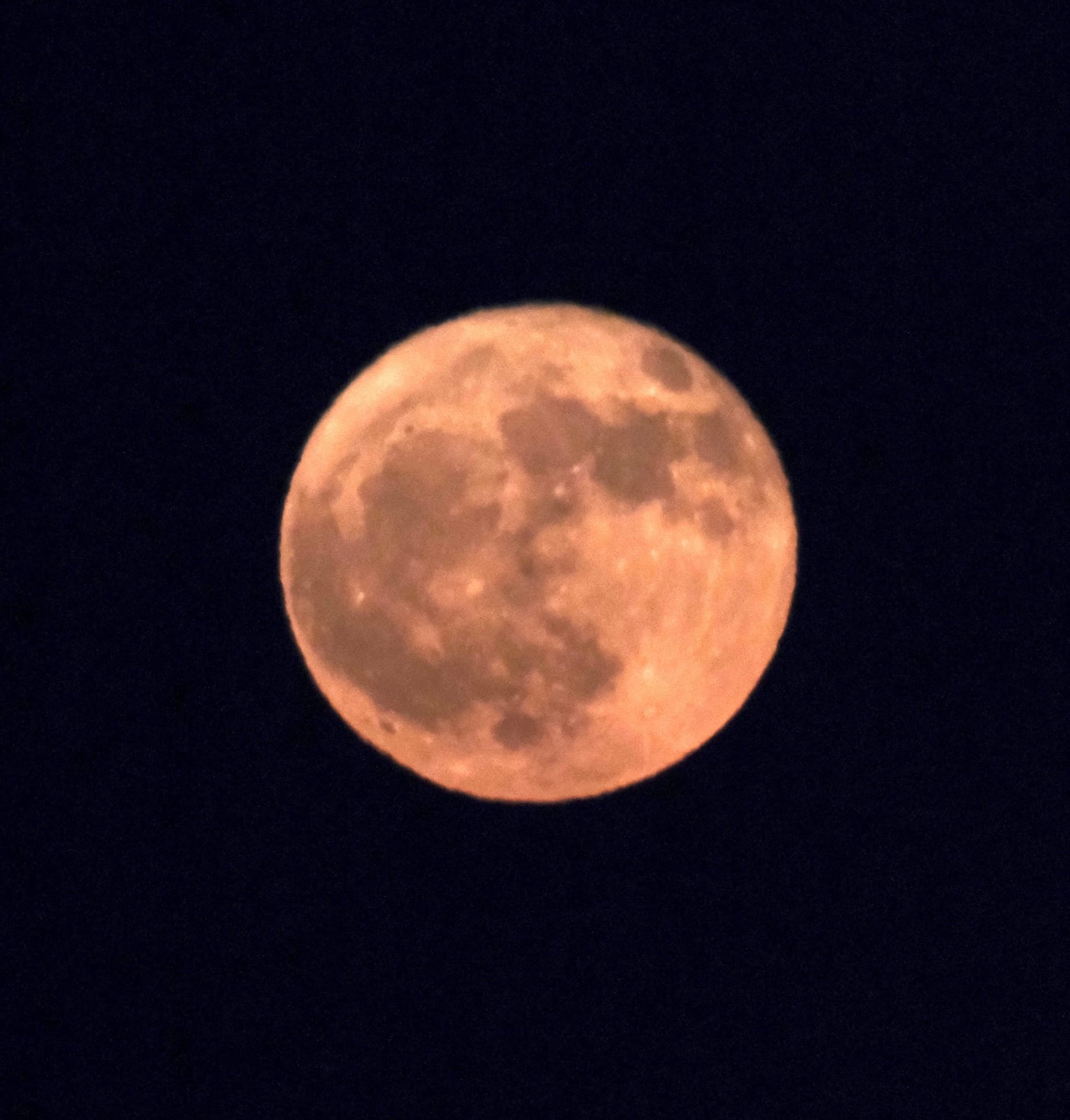 A full moon with a warm, orange hue against a dark night sky