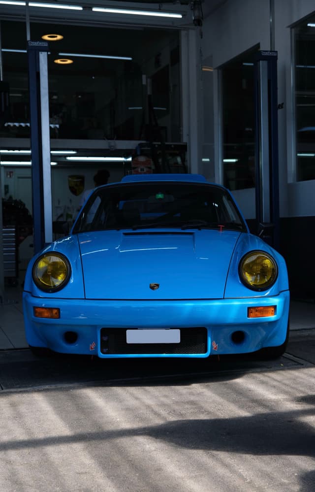 A blue sports car with yellow headlights is parked in a garage