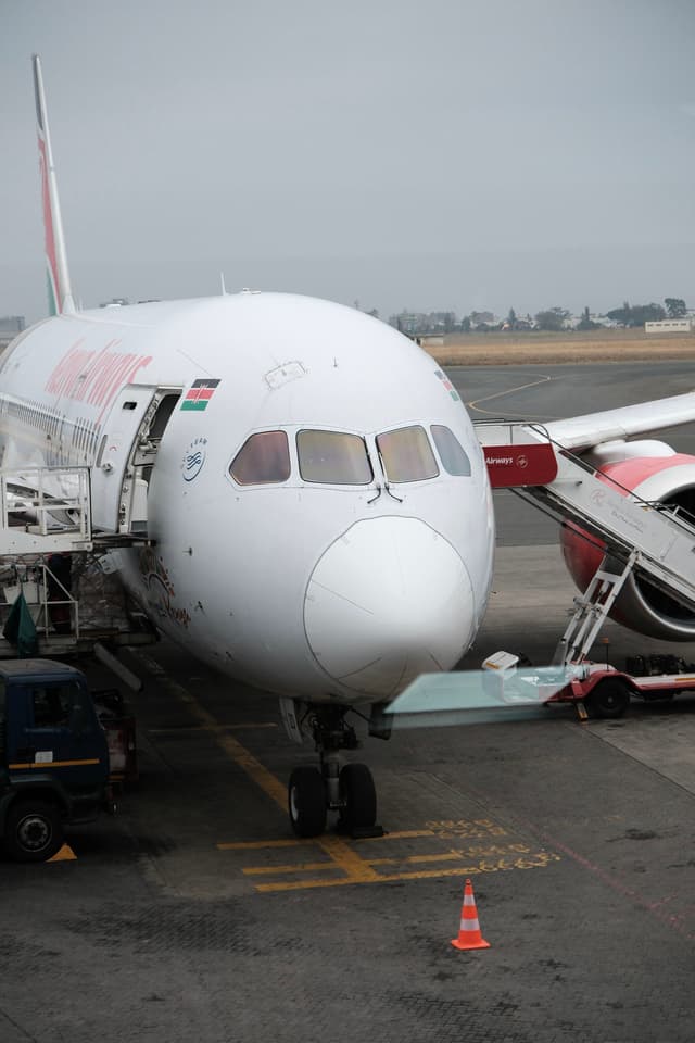 A commercial airplane is parked at an airport gate with a boarding ramp connected to it