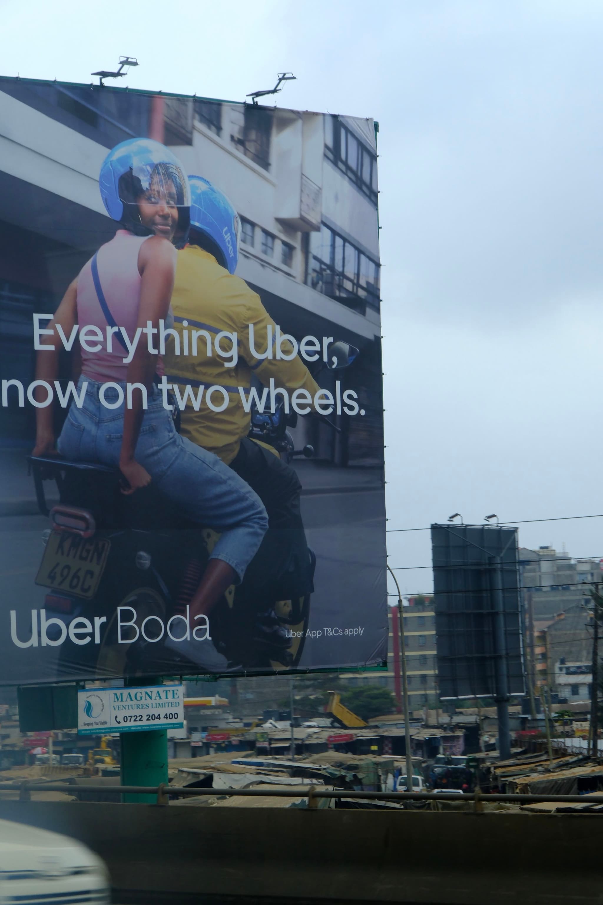 A large billboard advertises Uber Boda, featuring two people on a motorcycle with helmets, set against an urban backdrop