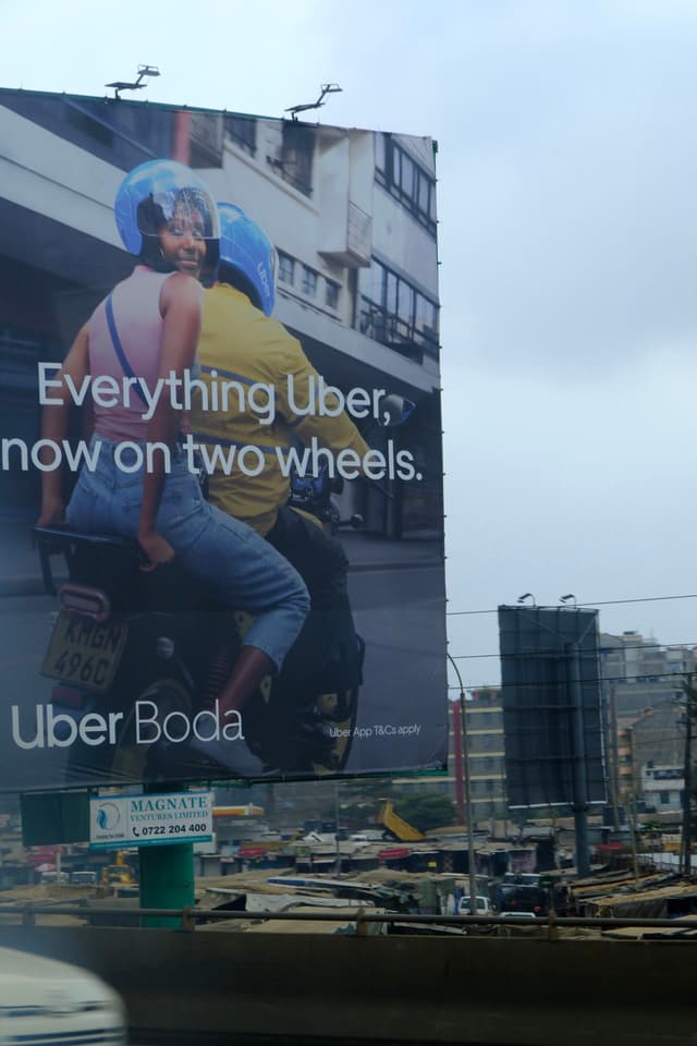 A large billboard advertises Uber Boda, featuring two people on a motorcycle with helmets, set against an urban backdrop