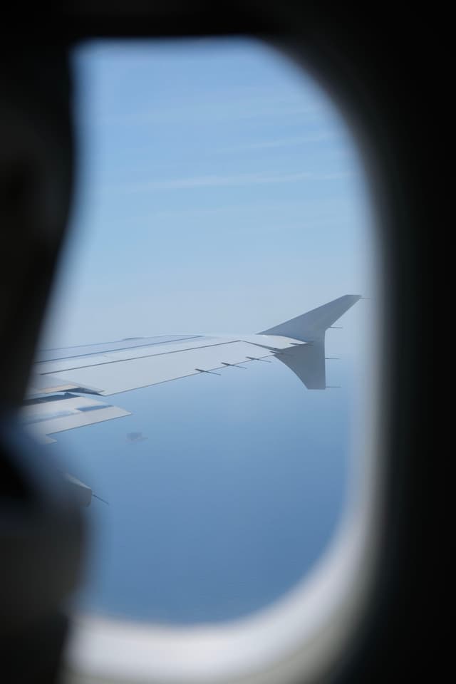 A view from an airplane window, showing the wing against a clear blue sky