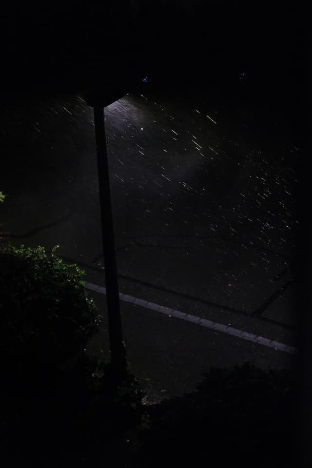 A streetlight illuminates raindrops at night, creating a serene atmosphere